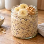 Peanut butter chia overnight oats in a glass jar, topped with banana slices and peanut butter.